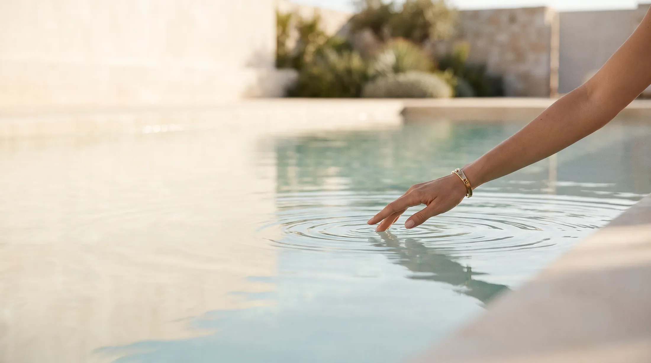 A hand touching still pool water